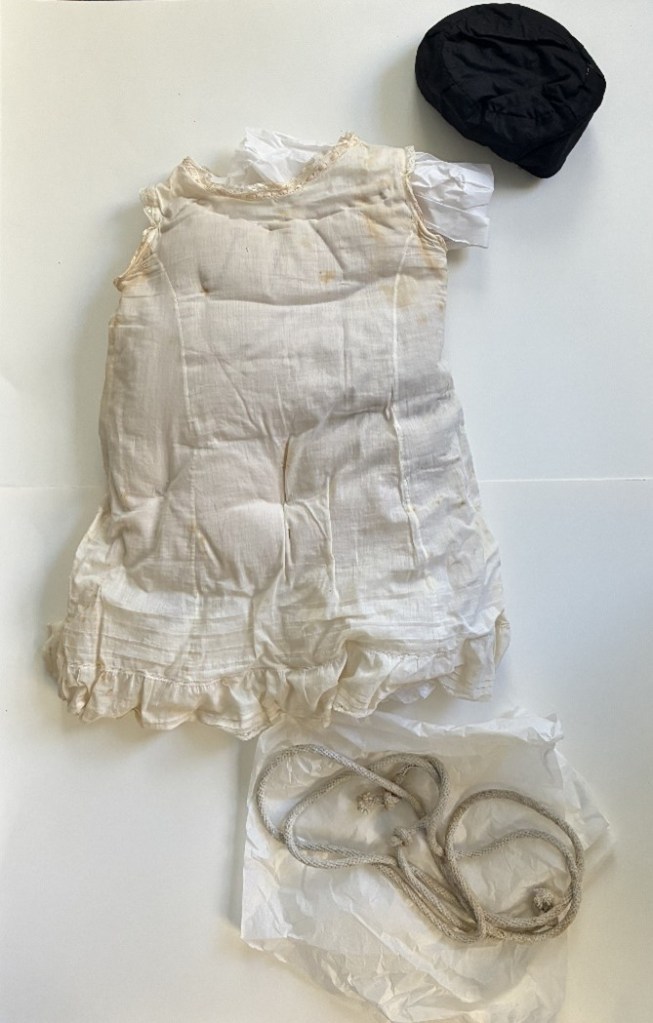 Off-white, light fabric slip and rope tie. Both have white tissue paper within or under them.