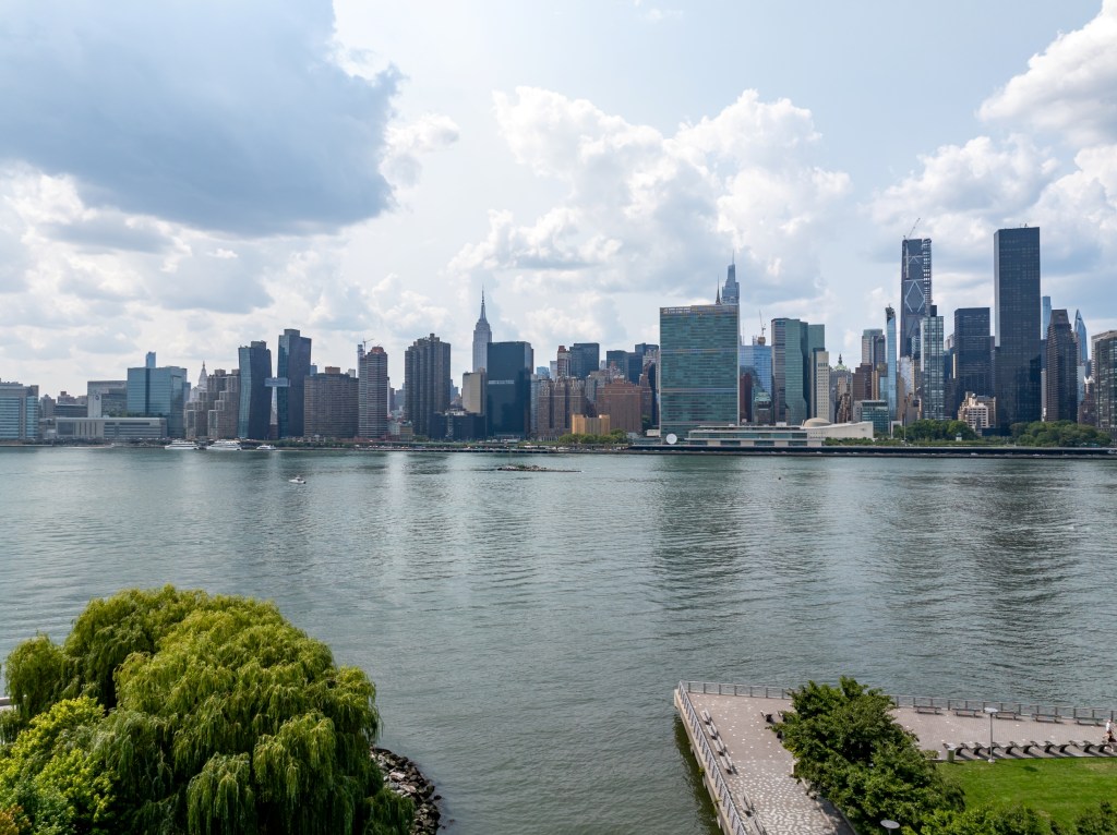 View of the Manhattan skyline from Gantry Plaza State Park, featuring skyscrapers and the East River.